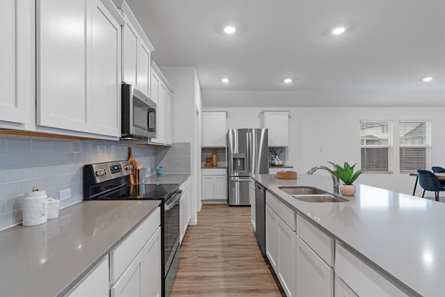 501 Bluejack Way, Hutto, TX 78634 - kitchen featuring appliances with stainless steel finishes, a sink, recessed lighting, light wood finished floors, and white cabinetry