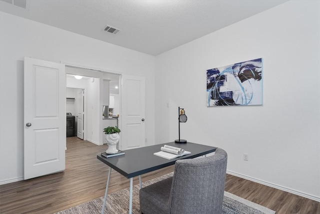 office with a textured ceiling, dark wood-style flooring, visible vents, and baseboards