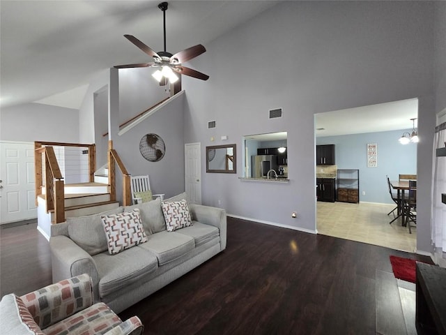 living room with lofted ceiling, hardwood / wood-style floors, and ceiling fan with notable chandelier