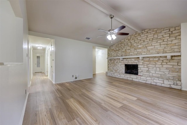 unfurnished living room featuring vaulted ceiling with beams, a large fireplace, ceiling fan, and light wood-type flooring