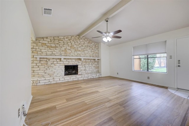 unfurnished living room featuring lofted ceiling with beams, ceiling fan, a brick fireplace, and light hardwood / wood-style floors