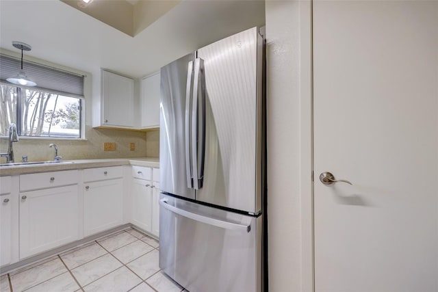 kitchen with sink, white cabinets, stainless steel fridge, decorative backsplash, and hanging light fixtures