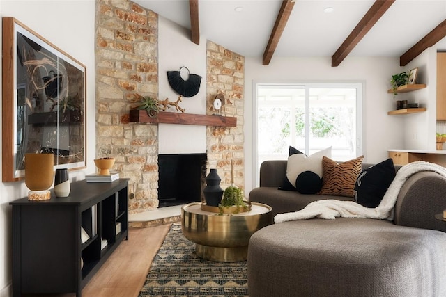 living room with a fireplace, beamed ceiling, and light wood-type flooring