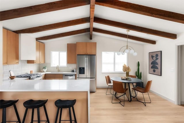 kitchen with sink, stainless steel appliances, tasteful backsplash, a kitchen bar, and kitchen peninsula