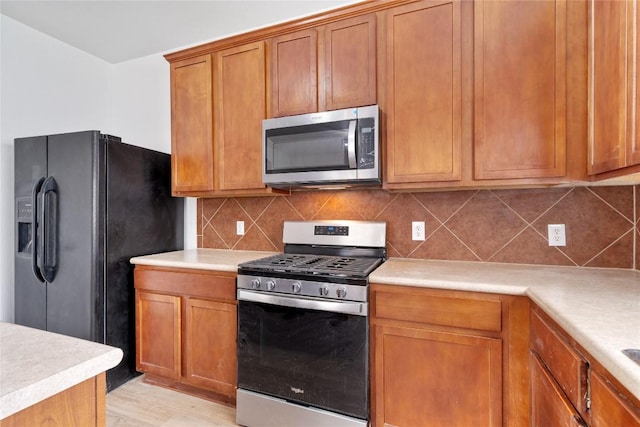 kitchen featuring decorative backsplash, stainless steel appliances, and light hardwood / wood-style floors