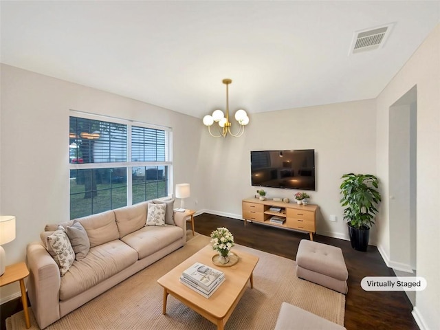 living room with an inviting chandelier, baseboards, visible vents, and wood finished floors