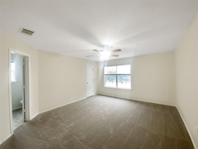 spare room featuring baseboards, visible vents, dark colored carpet, and a ceiling fan