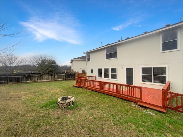 rear view of house with an outdoor fire pit, a lawn, and a wooden deck