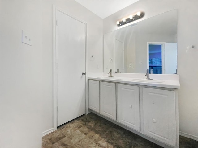 full bath with double vanity, a sink, and baseboards