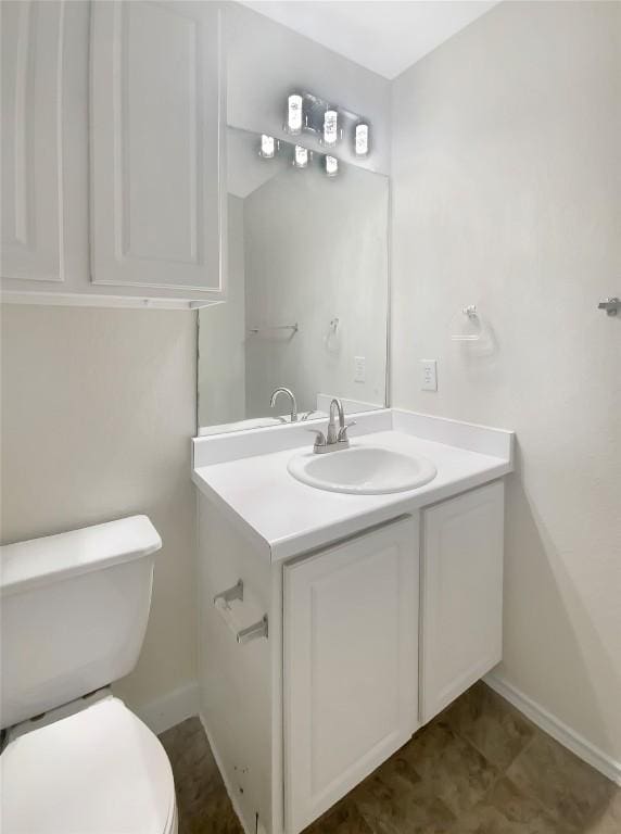 half bathroom featuring baseboards, vanity, and toilet