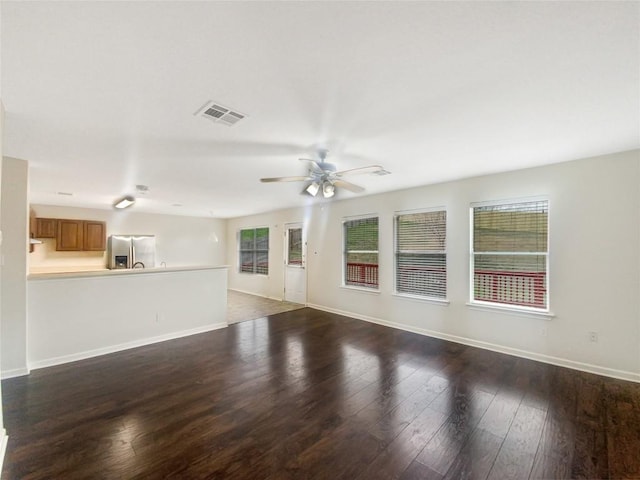 unfurnished living room featuring a ceiling fan, dark wood-style flooring, visible vents, and baseboards