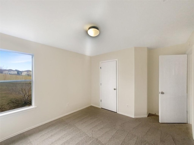 unfurnished bedroom with dark colored carpet and baseboards