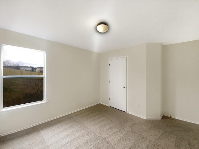 carpeted empty room featuring baseboards