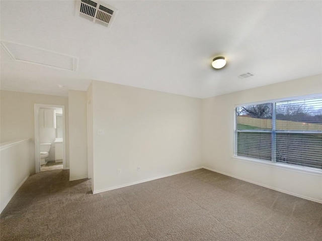 empty room featuring baseboards, attic access, visible vents, and carpet flooring