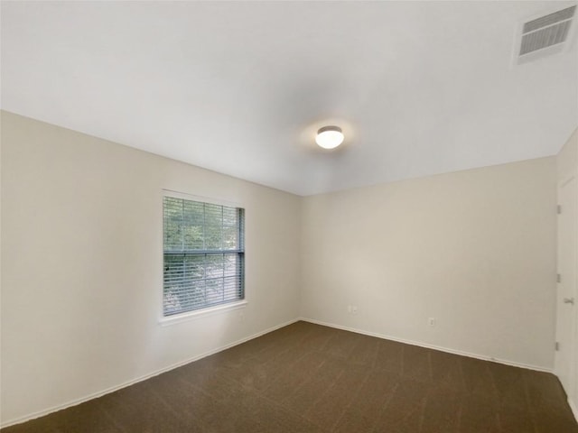 unfurnished room featuring dark colored carpet, visible vents, and baseboards