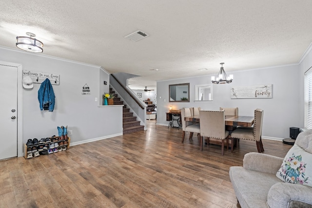 dining area featuring crown molding, a chandelier, a textured ceiling, and hardwood / wood-style flooring