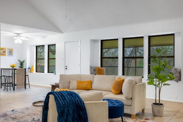 living room featuring ceiling fan, vaulted ceiling, and a textured ceiling