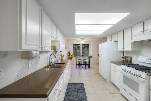 kitchen with sink, white appliances, tasteful backsplash, white cabinets, and light tile patterned flooring