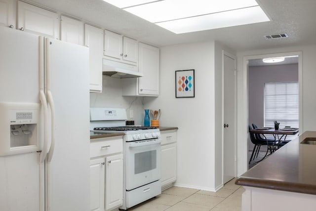 kitchen featuring white cabinetry, light tile patterned floors, white appliances, and a textured ceiling