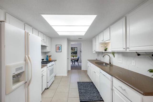 kitchen with sink, a textured ceiling, light tile patterned floors, white appliances, and white cabinets