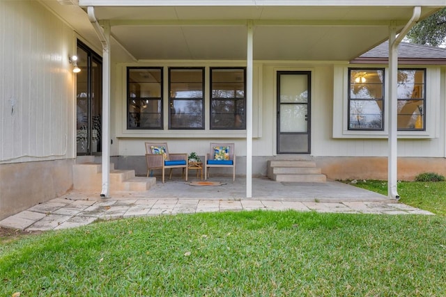 entrance to property featuring a lawn and a patio area