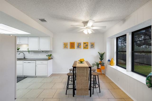 tiled dining room with ceiling fan, sink, and a textured ceiling