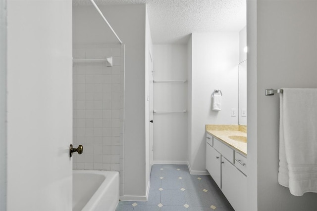 bathroom with vanity, tiled shower / bath combo, and a textured ceiling