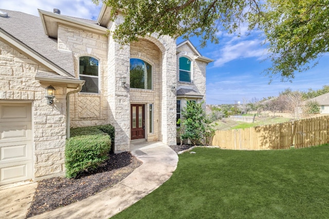 entrance to property with a garage and a lawn