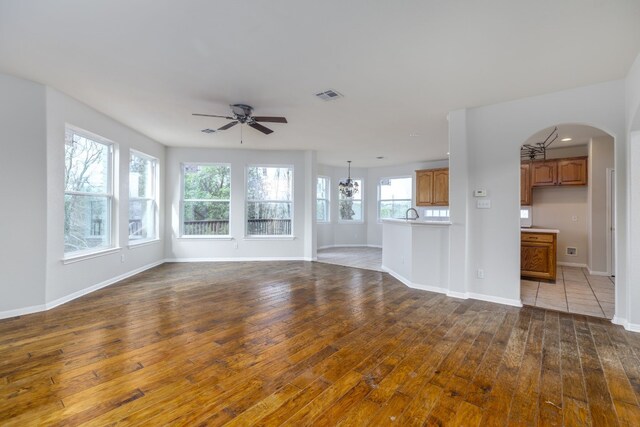 2901 Cashell Wood Dr, Cedar Park, TX 78613 - unfurnished living room featuring hardwood / wood-style flooring, a ceiling fan, baseboards, arched walkways, and a chandelier