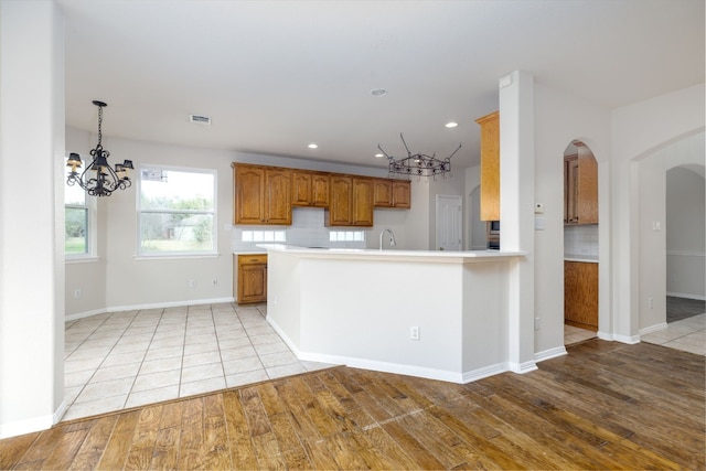 2901 Cashell Wood Dr, Cedar Park, TX 78613 - kitchen with a chandelier, arched walkways, brown cabinetry, light countertops, and recessed lighting