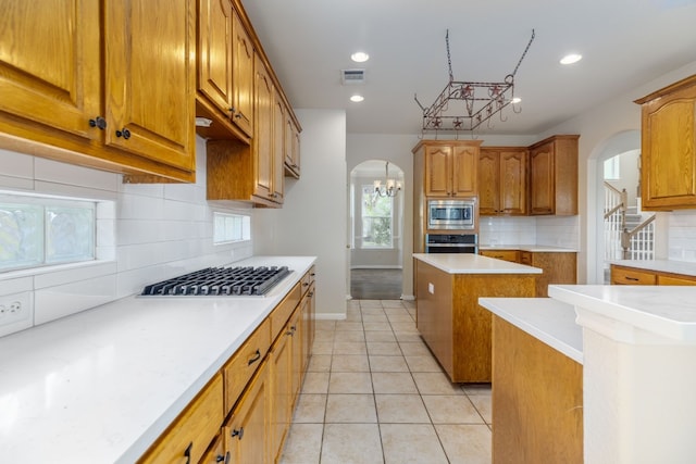 2901 Cashell Wood Dr, Cedar Park, TX 78613 - kitchen with arched walkways, appliances with stainless steel finishes, backsplash, brown cabinetry, and recessed lighting