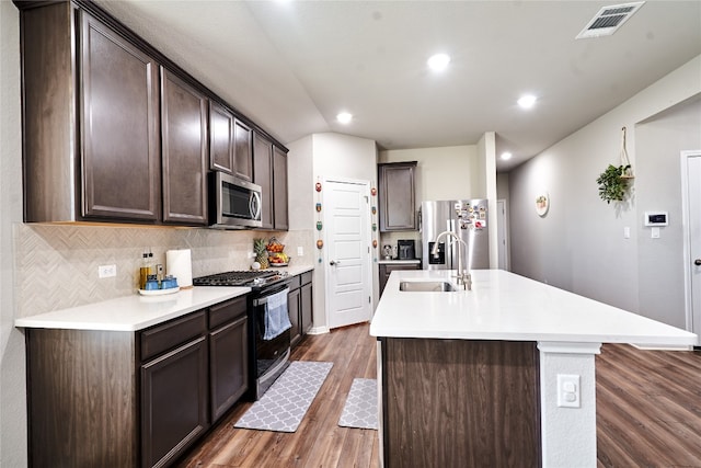 kitchen with stainless steel appliances, sink, a center island with sink, and dark brown cabinetry