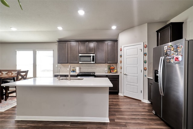 kitchen featuring dark brown cabinetry, sink, tasteful backsplash, a center island with sink, and stainless steel appliances