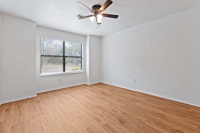 spare room featuring light wood-type flooring, ceiling fan, visible vents, and baseboards