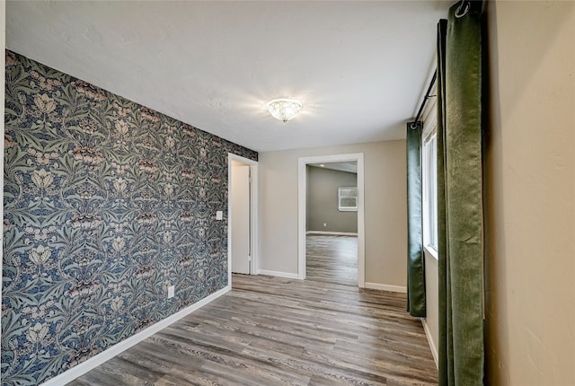 148 W Castleshoals Dr, Granite Shoals, TX 78654 - unfurnished room with an accent wall, baseboards, wallpapered walls, and wood finished floors