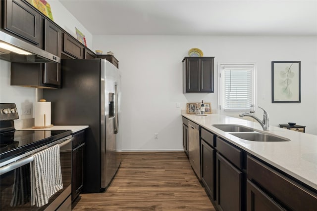 kitchen featuring extractor fan, sink, dark brown cabinets, appliances with stainless steel finishes, and dark hardwood / wood-style flooring