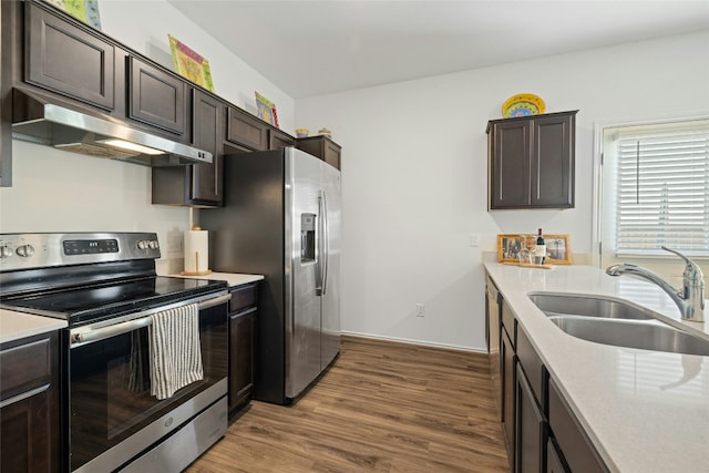 kitchen featuring dark brown cabinetry, sink, hardwood / wood-style flooring, and appliances with stainless steel finishes