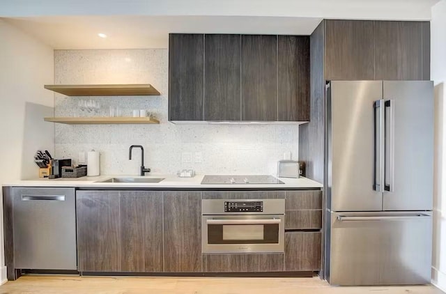 kitchen featuring sink, decorative backsplash, dark brown cabinetry, stainless steel appliances, and light hardwood / wood-style flooring