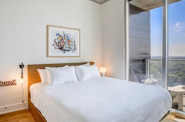 bedroom with expansive windows and light hardwood / wood-style floors