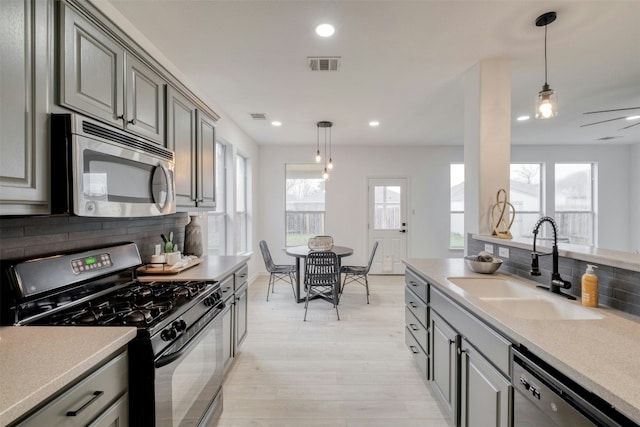 13701 Glen Mark Dr, Manor, TX 78653 - kitchen featuring appliances with stainless steel finishes, gray cabinets, decorative backsplash, light wood finished floors, and recessed lighting