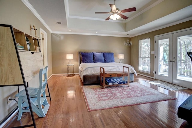 bedroom with a tray ceiling, access to outside, french doors, and wood-type flooring