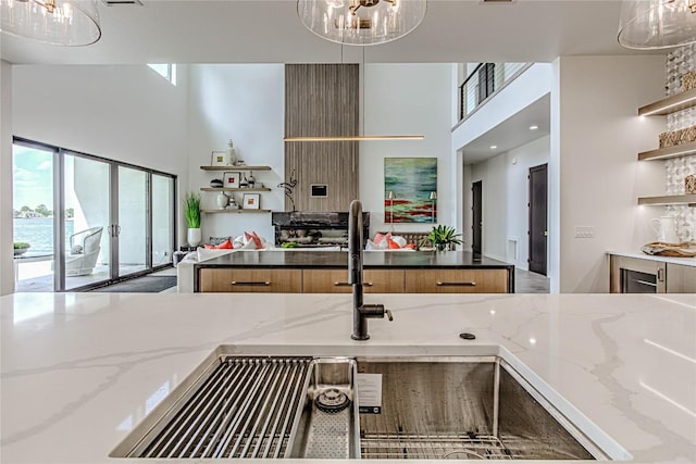 1012 Impala Dr, Granite Shoals, TX 78654 - kitchen featuring a high ceiling, open shelves, light stone counters, a chandelier, and hanging light fixtures