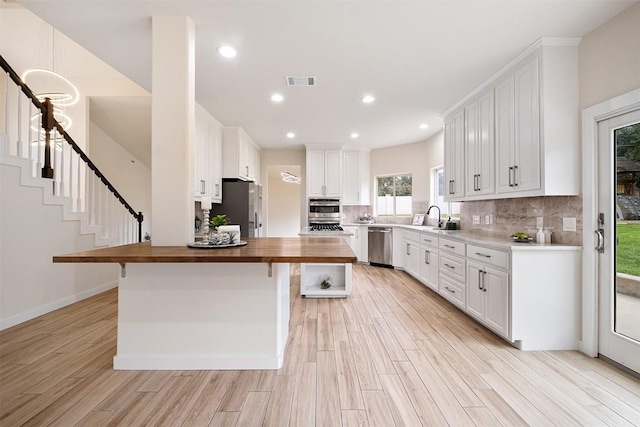 1302 Olympus Dr, Austin, TX 78733 - kitchen featuring wooden counters, stainless steel appliances, light wood-type flooring, a kitchen bar, and recessed lighting
