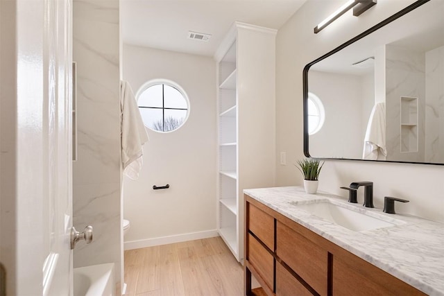 1302 Olympus Dr, Austin, TX 78733 - bathroom featuring vanity, wood finished floors, toilet, baseboards, and bathing tub / shower combination