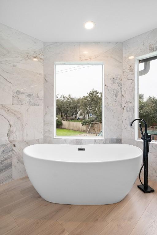 1302 Olympus Dr, Austin, TX 78733 - full bath with tile walls, a soaking tub, and wood finished floors