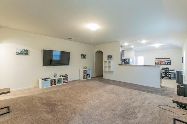 living area with carpet, visible vents, and arched walkways