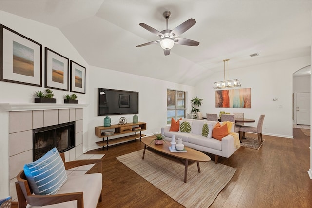 living room featuring a fireplace, vaulted ceiling, dark hardwood / wood-style floors, and ceiling fan