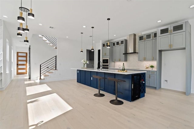 501 E Burton St, Manor, TX 78653 - kitchen with wall chimney range hood, light wood-style flooring, light countertops, backsplash, and recessed lighting