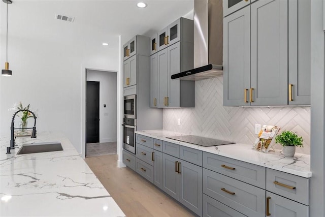 501 E Burton St, Manor, TX 78653 - kitchen featuring wall chimney exhaust hood, black electric stovetop, gray cabinets, light stone countertops, and backsplash