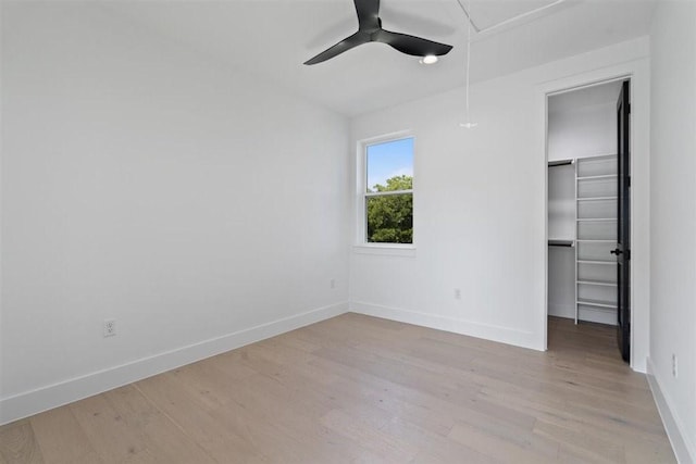 501 E Burton St, Manor, TX 78653 - unfurnished bedroom featuring light wood-style floors, a walk in closet, a ceiling fan, a closet, and attic access